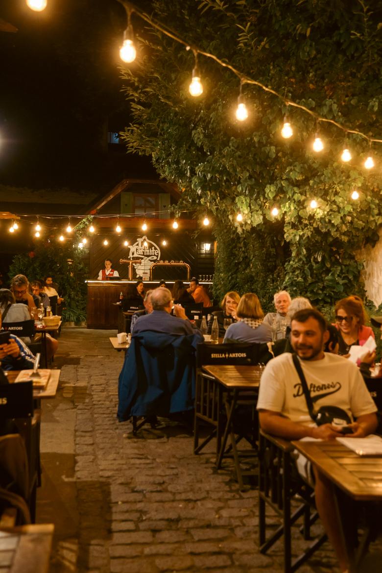 El Biergarten de noche, con mesas llenas bajo las guirnaldas